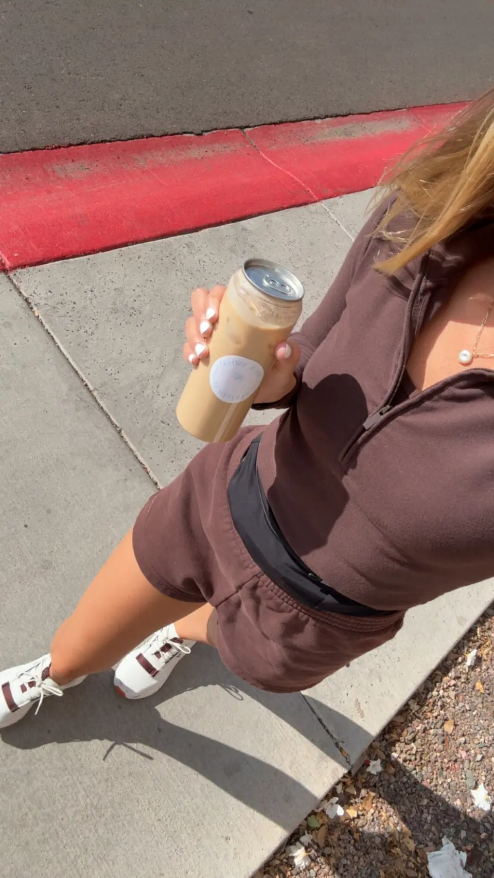 Lexi holding an iced latte in a Brew and Go can on a walk, seen from above