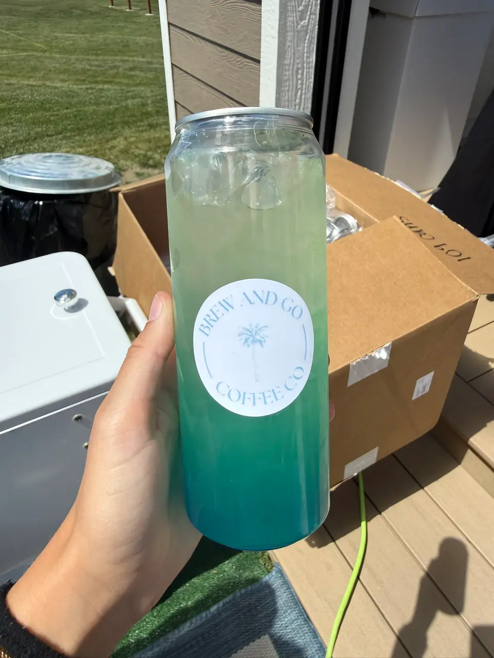 A pale green-to-teal drink in a Brew and Go can, held outdoors